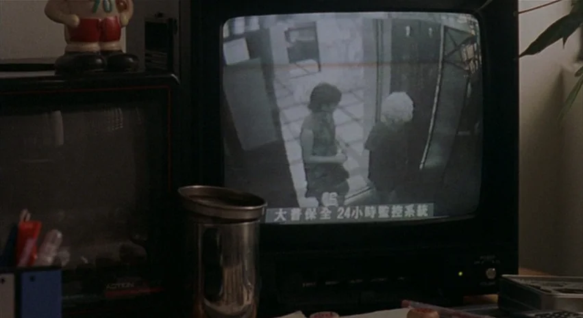 Yi-Yi (A One and A Two) (2000) movie still: medium — A close view of a dark CRT monitor showing a black-and-white security camera feed. The monitor…