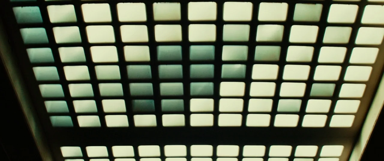 Gangster Squad (2013) movie still: closeup — A gridded, rectangular light fixture is mounted directly overhead on a flat ceiling. The individual…