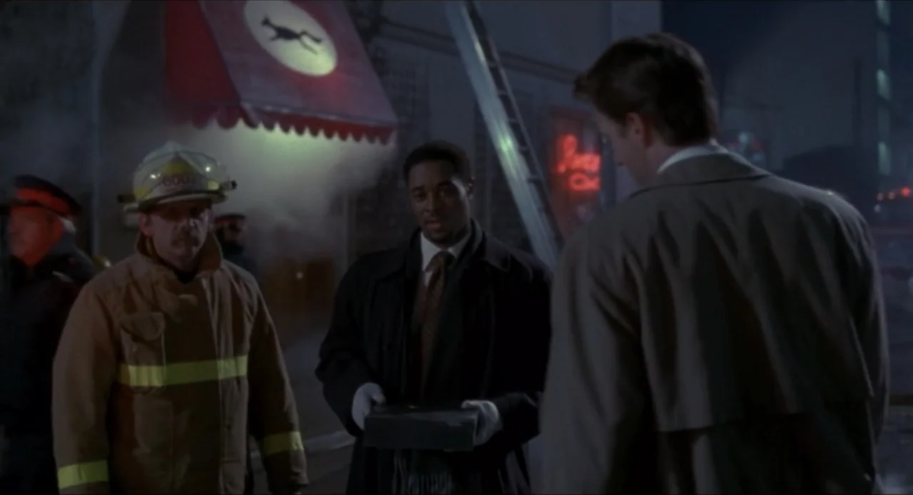 Foolproof (2003) movie still: medium — A dark urban street at night with an illuminated red awning and ladder visible. Three men stand near each…