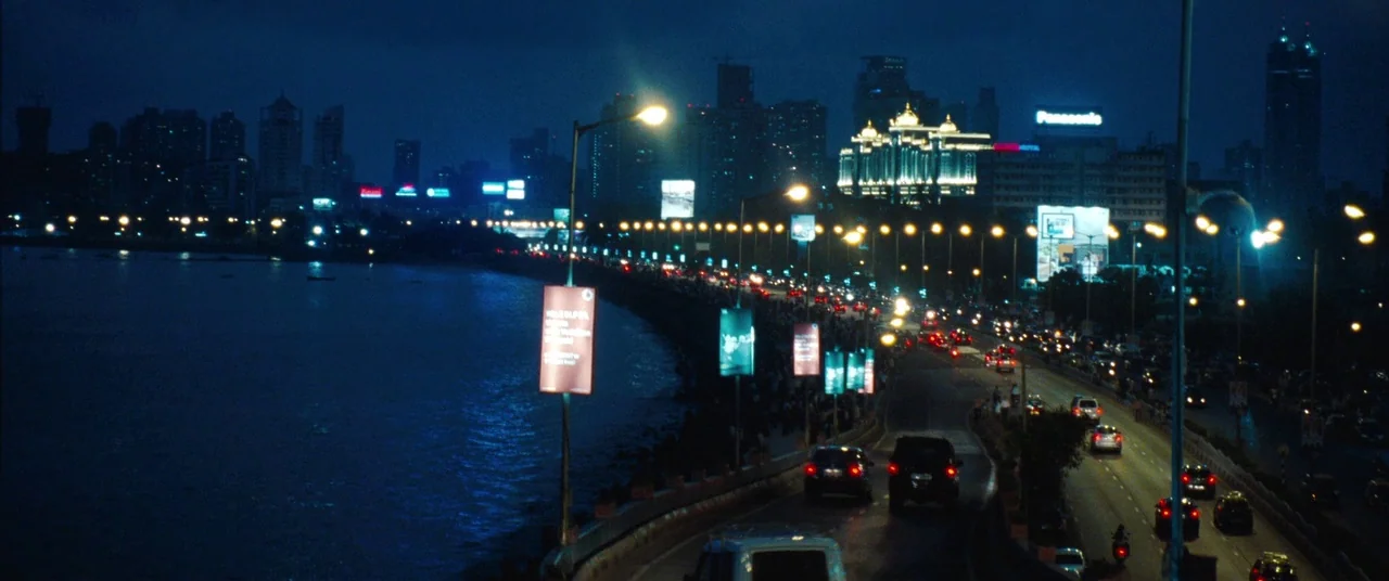 Mission: Impossible – Ghost Protocol (2011) movie still: wide — A night view of a coastal road in Mumbai running alongside the dark sea. Modern city…