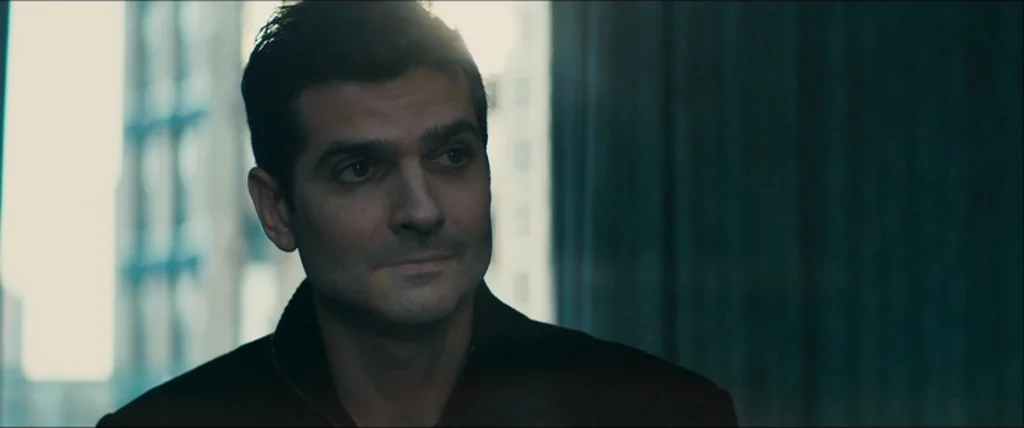 The Girlfriend Experience (2009) movie still: closeup — A modern office interior with a glass window looking out at high-rise buildings. A man in a…
