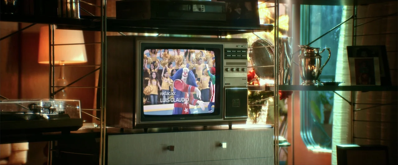 Bingo: The King of the Mornings (2017) movie still: medium — A retro 1980s living room features a wooden television set sitting on a shelf. A…