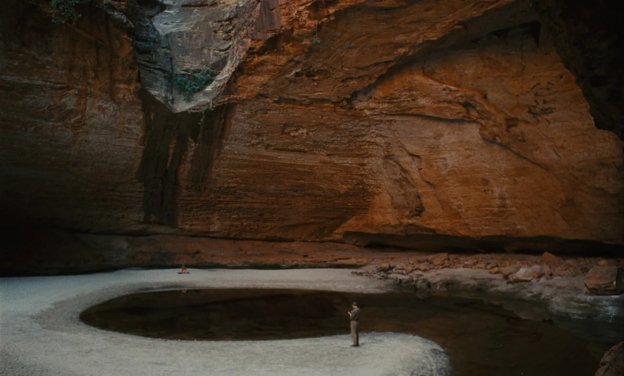 Until The End Of The World (1991) movie still: wide — A vast natural grotto features high, textured sandstone walls and a central still pool. A man…