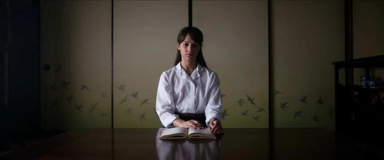 Earthquake Bird movie still: medium — A dark Japanese room features sliding shoji screens painted with flying bird motifs. A young woman sits at a…