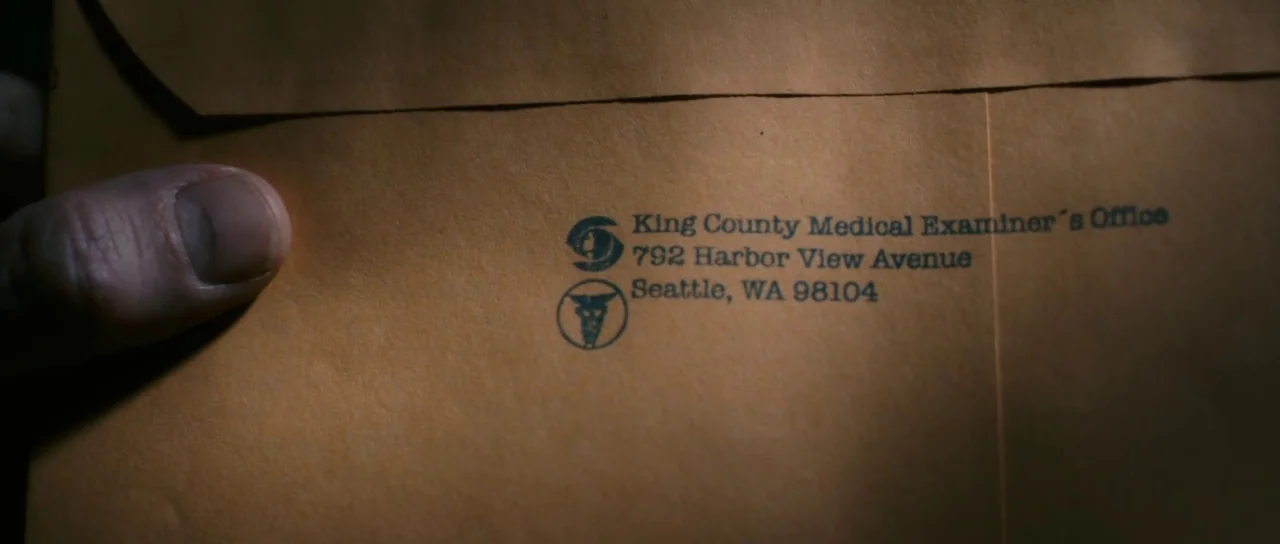 Antichrist (2009) movie still: closeup — A close-up view of a manila envelope with printed address details. A human thumb holds the edge of the…