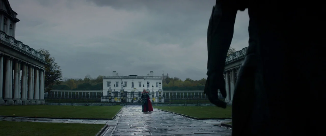 Thor: The Dark World (2013) movie still: wide — A stone path leads to a large white mansion across a grassy courtyard. A warrior in ornate armor…