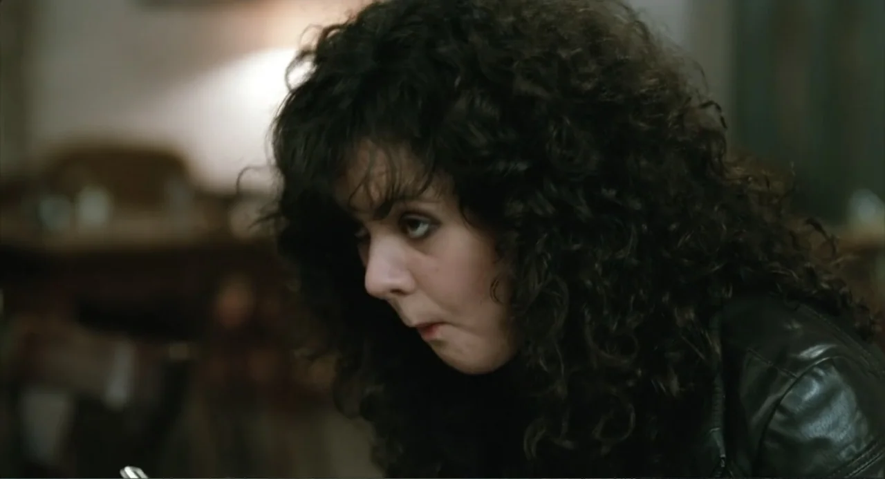 Soul Kitchen (2009) movie still: closeup — An interior space features a dark, indistinct background with blurred textures. A young woman with dark…