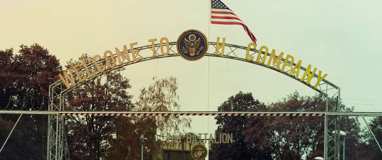 Ip Man 4: The Finale (2019) movie still: establishing — A metal archway displays 'Welcome to H Company' over a military installation entrance. An…