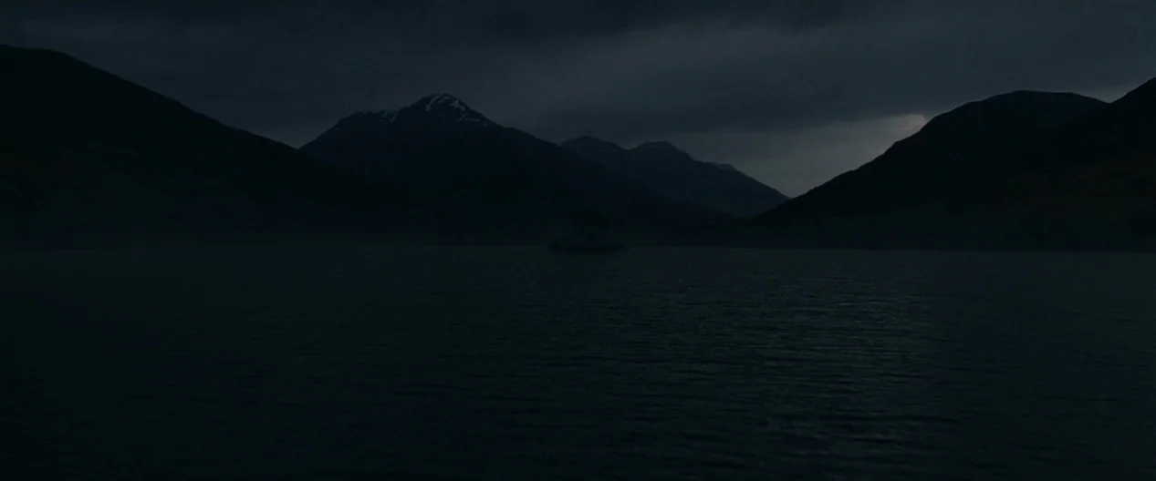 Harry Potter & The Deathly Hallows Part 1 (2010) movie still: establishing — A dark, expansive lake is surrounded by silhouetted mountain ranges…