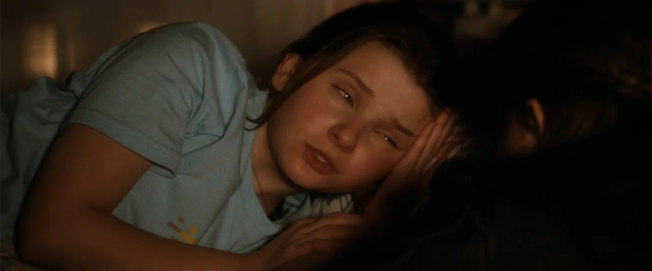 My Sister's Keeper (2023) movie still: closeup — A dark bedroom with soft bedding visible in the low light. A young girl rests her head on her hand…