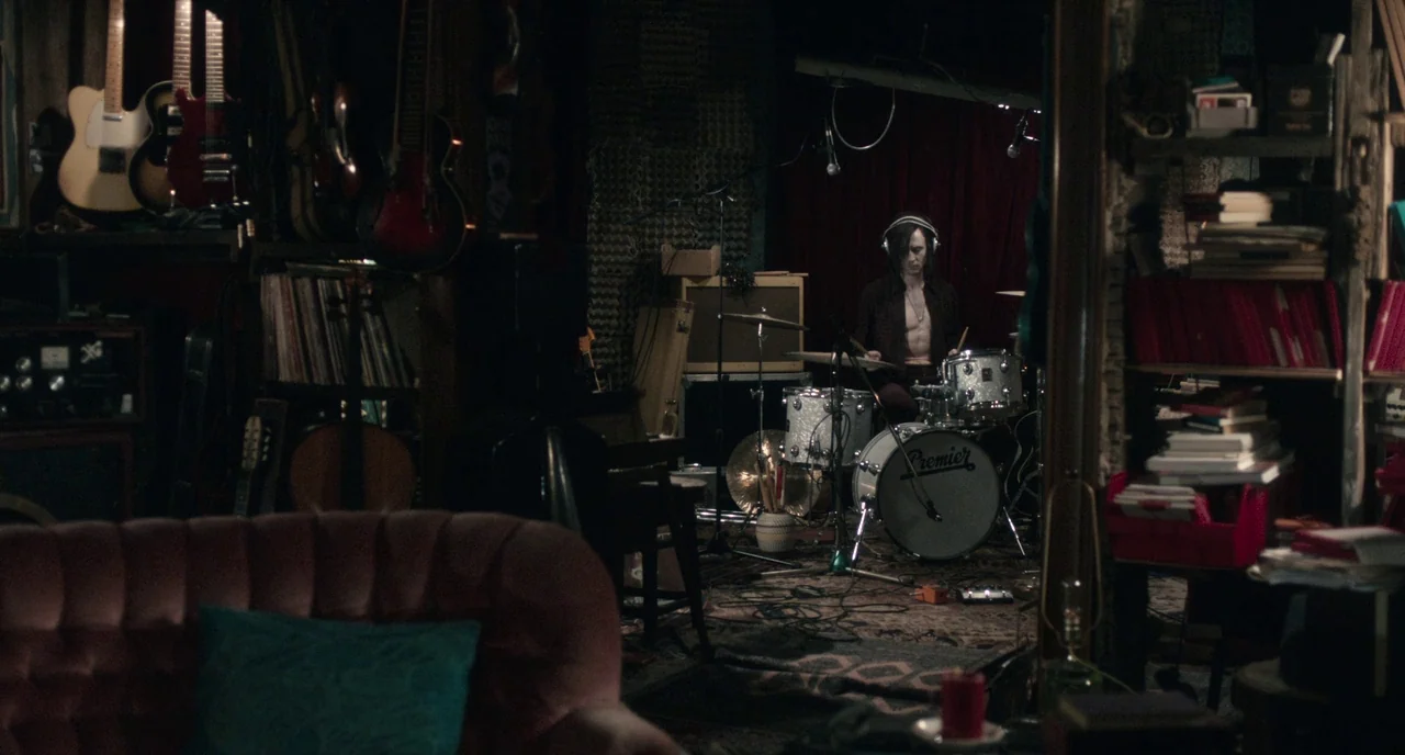 Only Lovers Left Alive (2013) movie still: wide — A dark music studio filled with guitars, records, and a vintage drum kit. A man plays the drums…