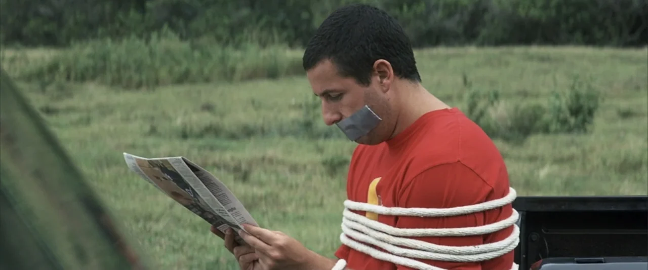 50 First Dates (2004) movie still: medium — An open grassy field serves as the backdrop for a man sitting outdoors. The man has his hands and chest…