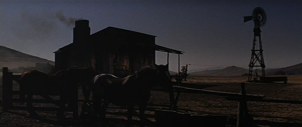 Flaming Star (1960) movie still: wide — A remote western ranch features a dark wooden cabin with a smoking chimney. A metal windmill stands in the…