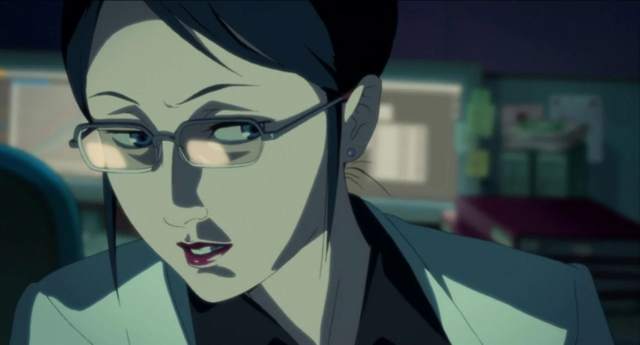 Paprika (2006) movie still: closeup — An office environment at night features a dark desk with cluttered papers and monitors. A woman with dark hair…