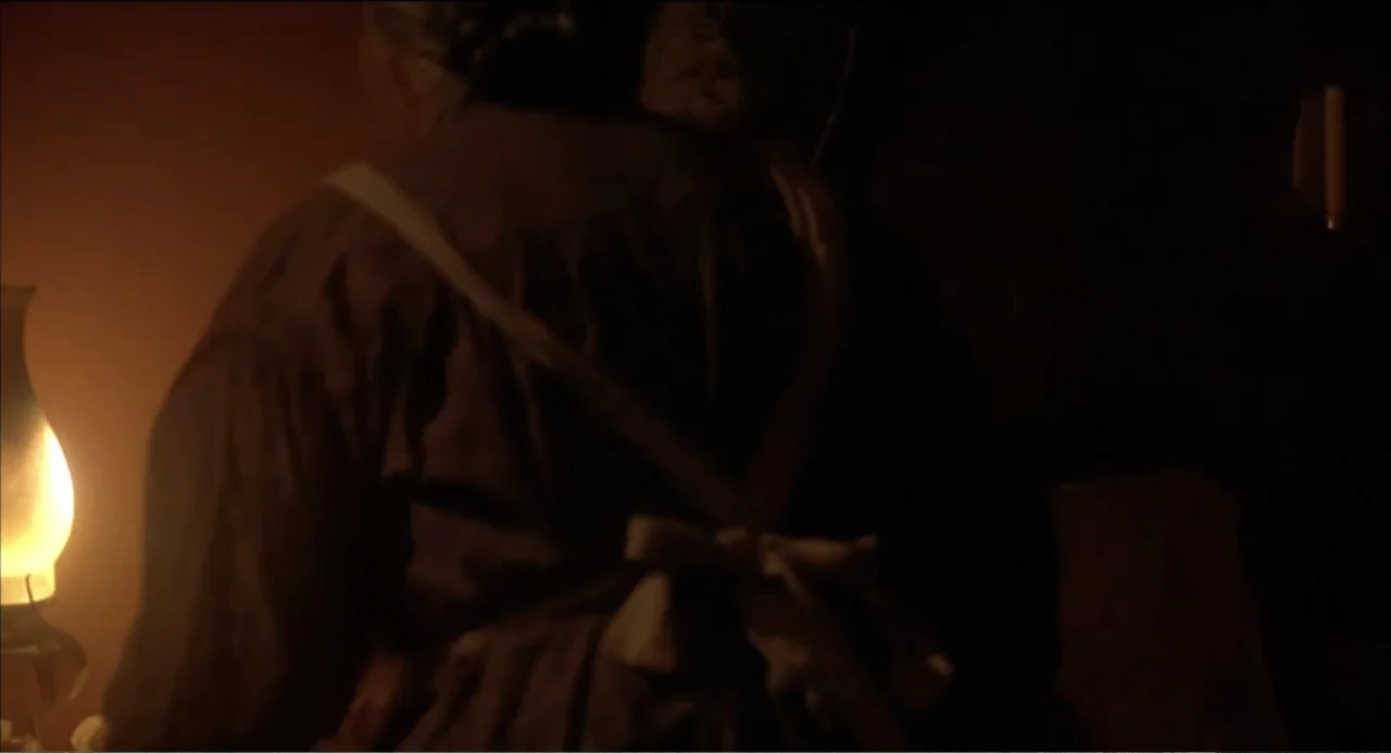 Like Water for Chocolate (1992) movie still: medium — A dimly lit room features a person standing near a glowing oil lamp. The individual wears a…