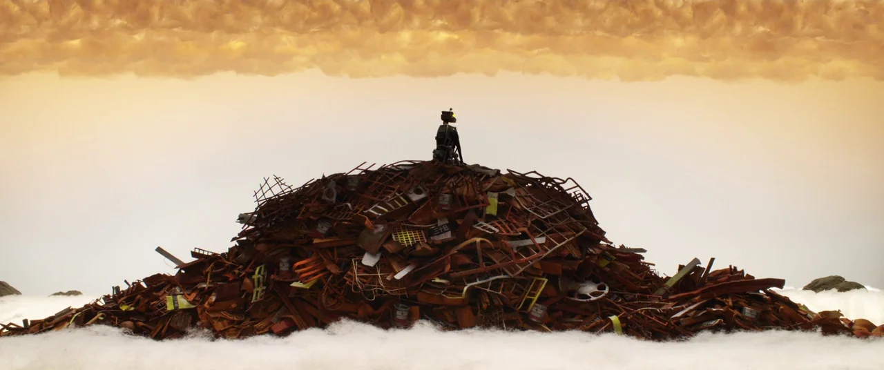 Isle of Dogs (2018) movie still: wide — A dense mound of rusted metal debris sits atop a bed of soft material. A solitary small figure rests on the…
