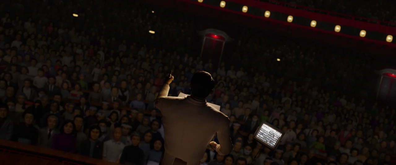 Isle of Dogs (2018) movie still: wide — A large, dark theater auditorium is filled with a dense crowd of silent people. A lone man in a light suit…