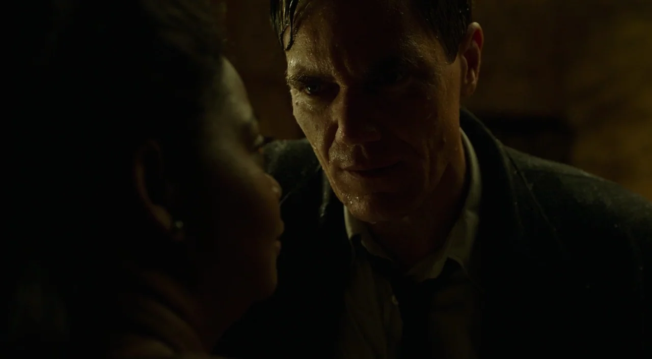The Shape of Water (2017) movie still: closeup — A dimly lit, shadowed interior space provides the backdrop for this encounter. A man with damp,…