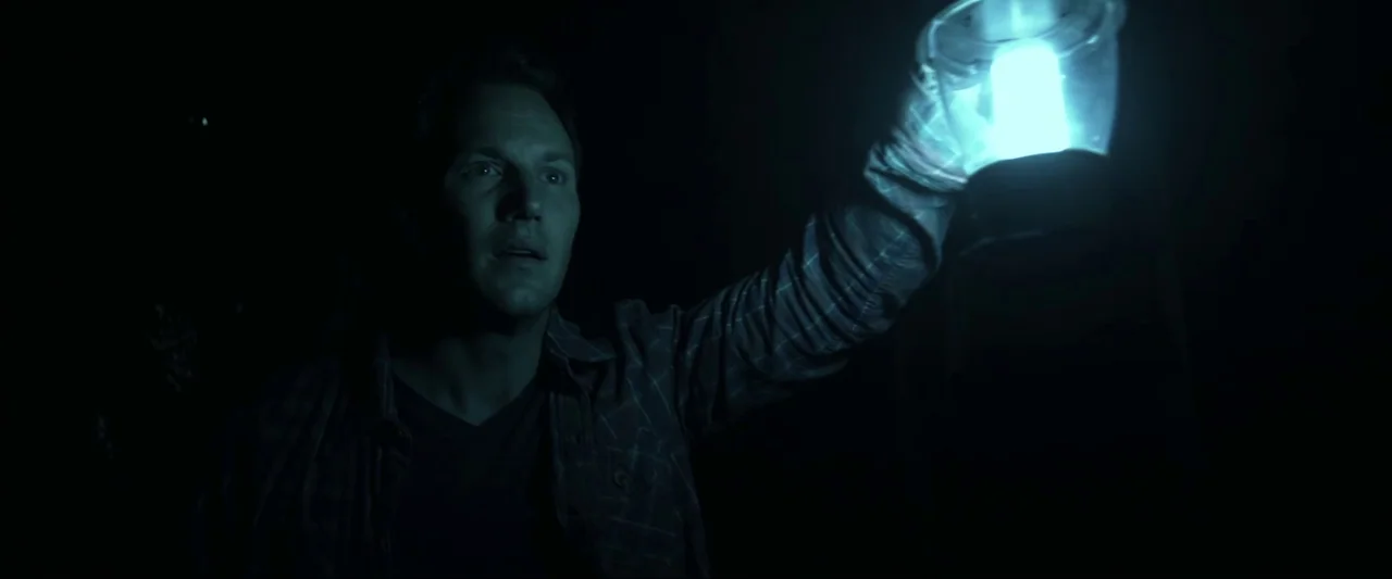 Insidious (2010) movie still: medium — A dark, featureless space is illuminated only by a handheld lantern. A man stares into the darkness while…