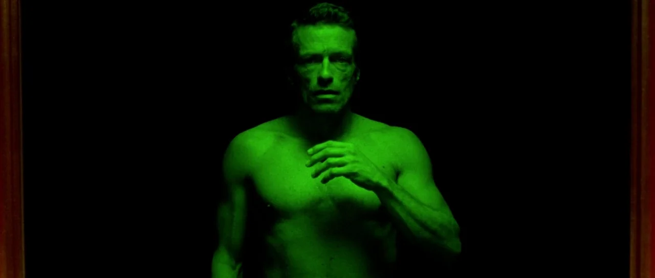 The Strange Colour of Your Body’s Tears (2013) movie still: medium — A man stands in a dark environment with no visible background details. The…