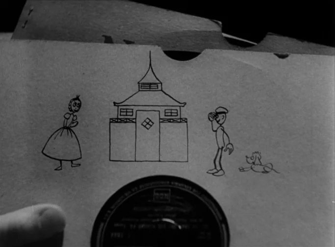 Summer Interlude (1951) movie still: closeup — A black-and-white photograph shows a hand holding a paper vinyl record sleeve. Simple black ink line…