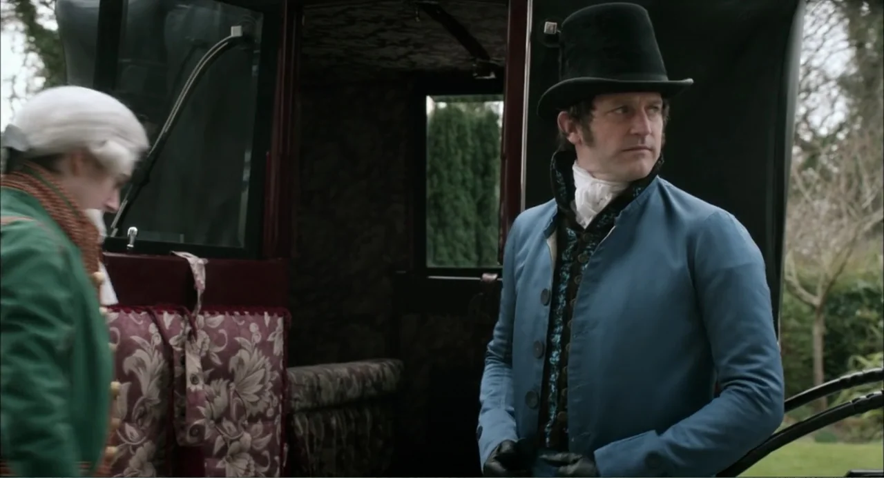 Love & Friendship (2016) movie still: medium — A man in a period top hat stands outside an open carriage door. He watches as another person in a wig…