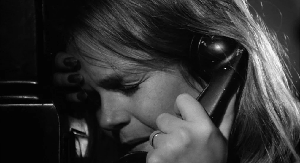 Lenny (1974) movie still: closeup — A dark, enclosed space with a vintage telephone mounted to a vertical surface. A woman rests her forehead…