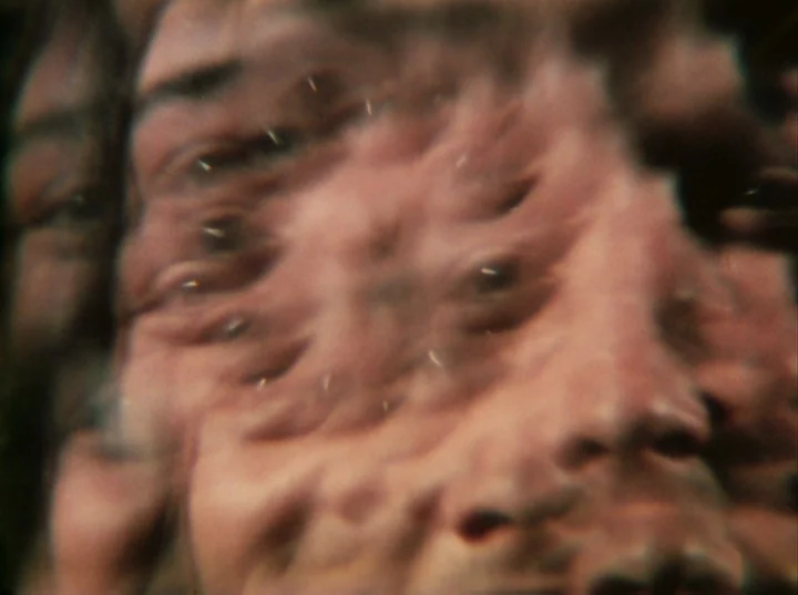 Invocation of My Demon Brother (1969) movie still: closeup — An abstract, multi-layered photographic exposure of a human face fills the frame.…