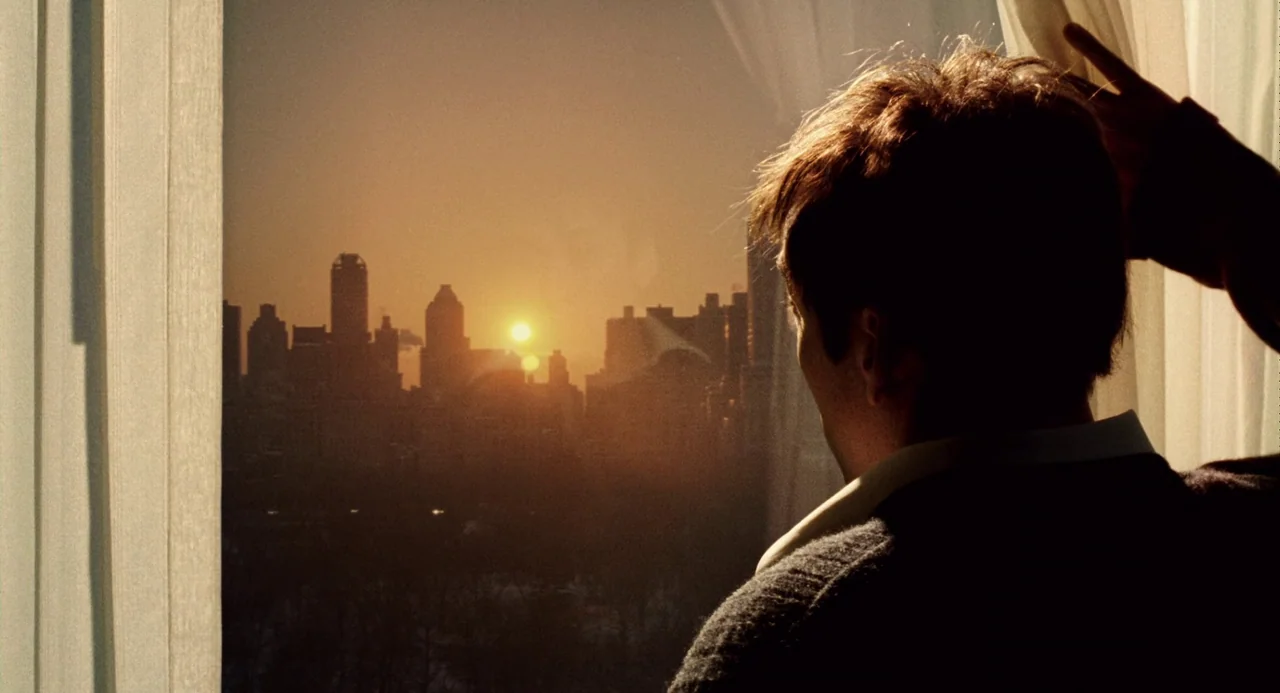 The Weather Man (2005) movie still: medium — A high-rise room overlooks a silhouette of a sprawling city at sunset. A man stands at the window…
