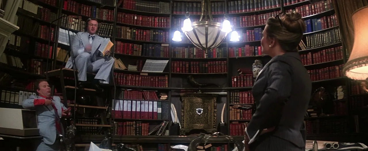 Superman (1978) movie still: wide — A curved library wall features floor to ceiling shelves packed with vintage books. A man sits high on a rolling…