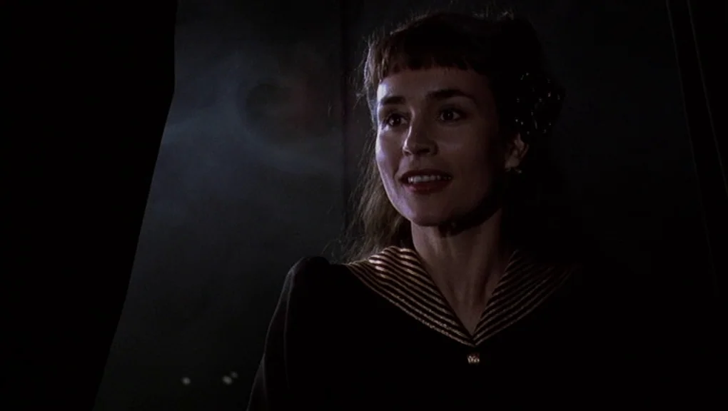Bird (1988) movie still: medium — A woman stands in a dim, shadowed area bordered by a heavy dark curtain. She turns toward an off-screen light…