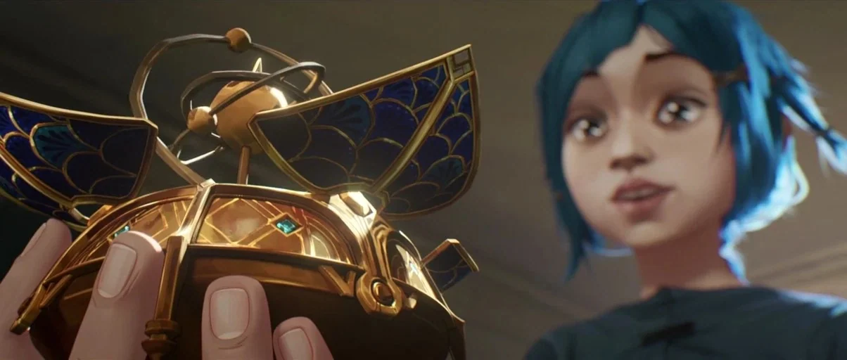 Arcane (2021) movie still: closeup — A close up view shows a pair of hands holding a complex golden device. A young girl with blue hair looks at the…