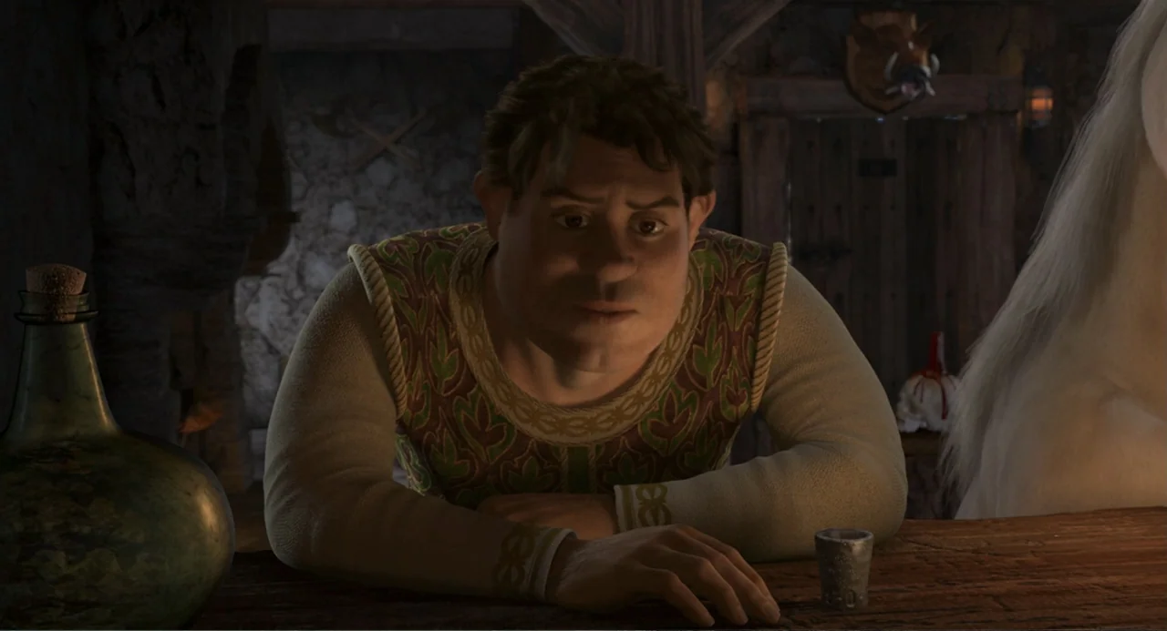 Shrek 2 (2004) movie still: medium — A dimly lit medieval tavern features a stone wall and a wooden bar surface. A man leans forward onto the…