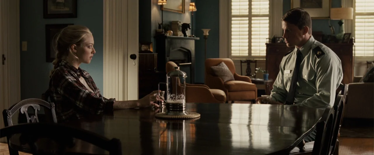 Dear John (2010) movie still: medium — A traditional dining room has blue walls, wooden furniture, and shuttered windows. A woman and a man in a…