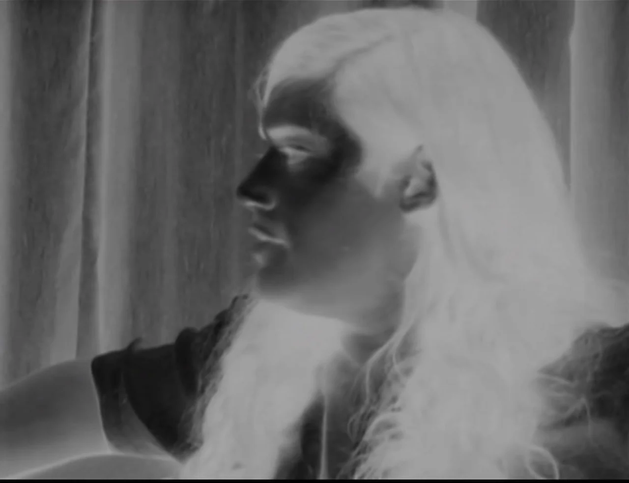 Computer Chess (2013) movie still: closeup — An interior space features a person in profile against a draped background. The subject faces left with…