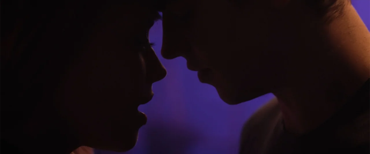 After Ever Happy (2022) movie still: closeup — Two individuals stand facing each other in a dark interior space with purple lighting. They appear to…