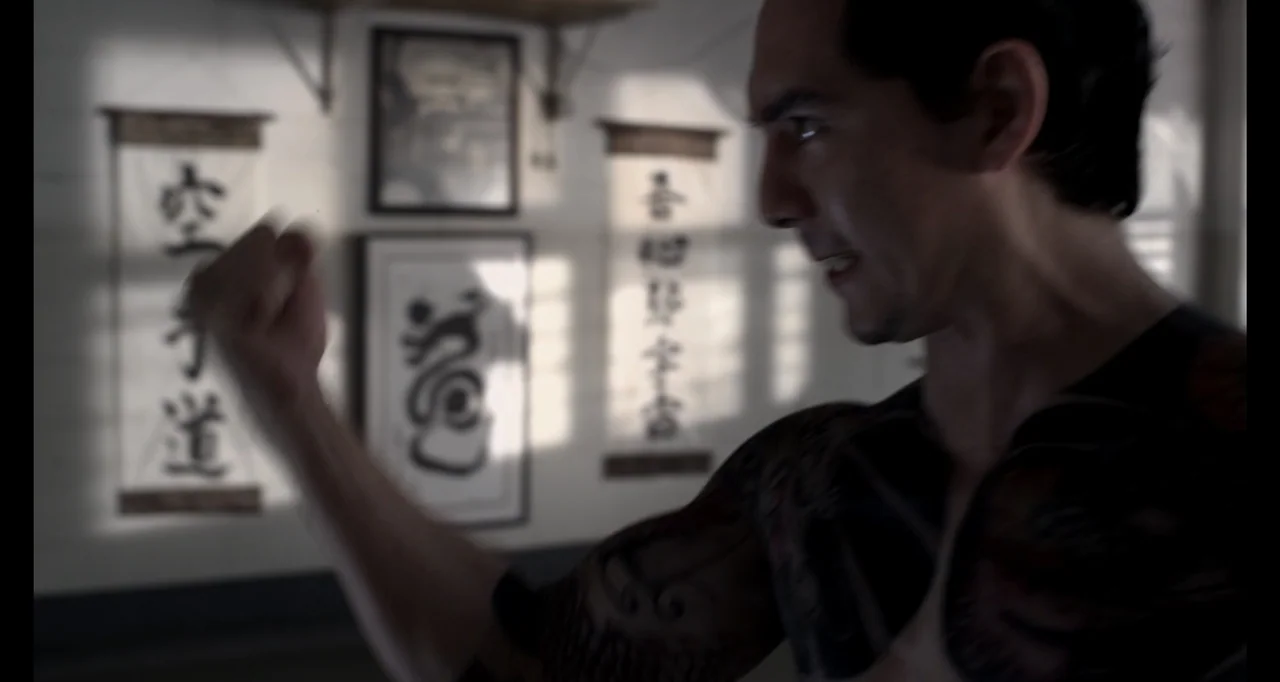 Ninja: Shadow of a Tear (2013) movie still: medium — A spare interior training space features white walls decorated with vertical Japanese…