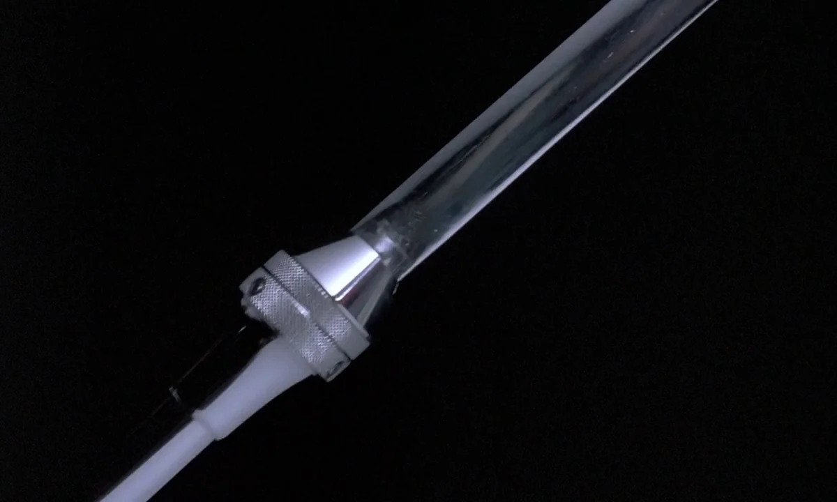 Phenomena (1985) movie still: closeup — A close-up view of a metallic syringe attachment featuring a knurled cylindrical connector. The transparent…