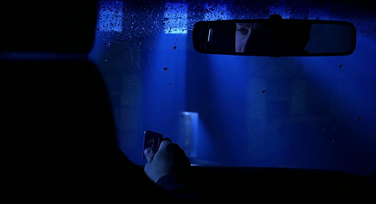 Bride of Chucky (1998) movie still: medium — A car interior at night is illuminated by a uniform blue light. A driver holds a small black remote…