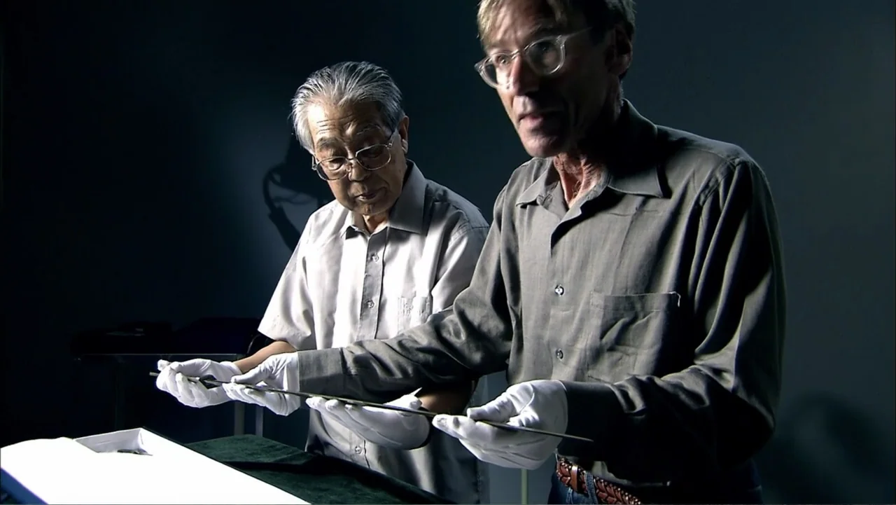 The First Emperor (2006) movie still: medium — An interior space features two men standing behind a table covered in dark fabric. The men hold a…