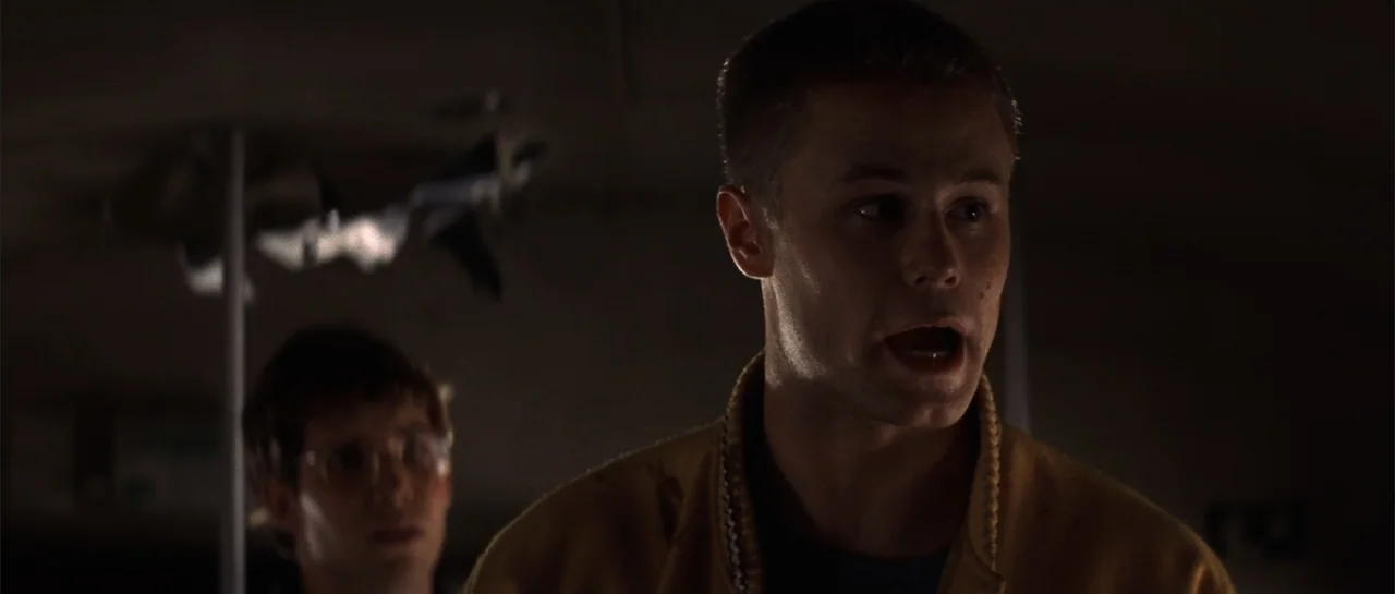 Jeepers Creepers 2 (2003) movie still: medium — A dark, dimly lit interior space with shadows obscuring most architectural details. A young man with…