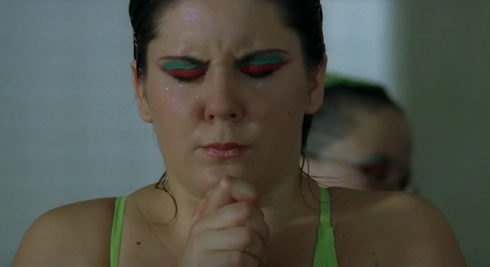 Water Lillies (2007) movie still: closeup — A close-up shot of a young woman inside a sterile locker room setting. She keeps her eyes closed while…
