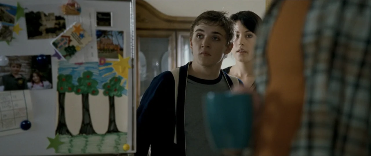 The Haunting in Connecticut (2009) movie still: medium — A domestic interior with a magnetic board covered in drawings and photographs. A young man…
