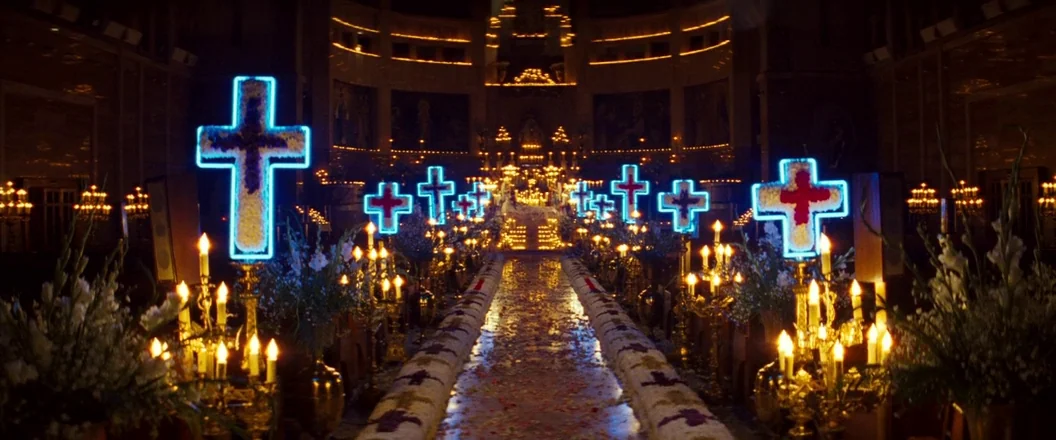 Romeo + Juliet (1996) movie still: establishing — A dark church interior is transformed with glowing neon crosses and numerous burning candles. A…
