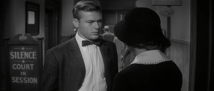Compulsion (1959) movie still: medium — A courthouse hallway features a sign reading silence court in session on the wall. A young man in a bow tie…