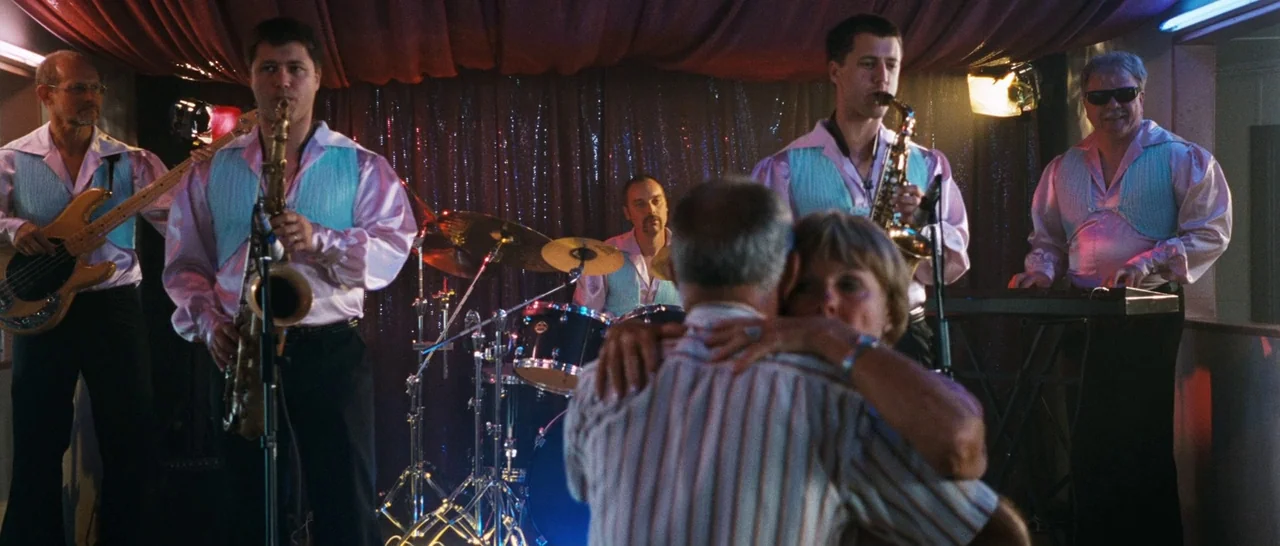 Sound of Noise (2010) movie still: medium — A dance floor features a band performing in front of a draped curtain backdrop. A couple slow dances in…