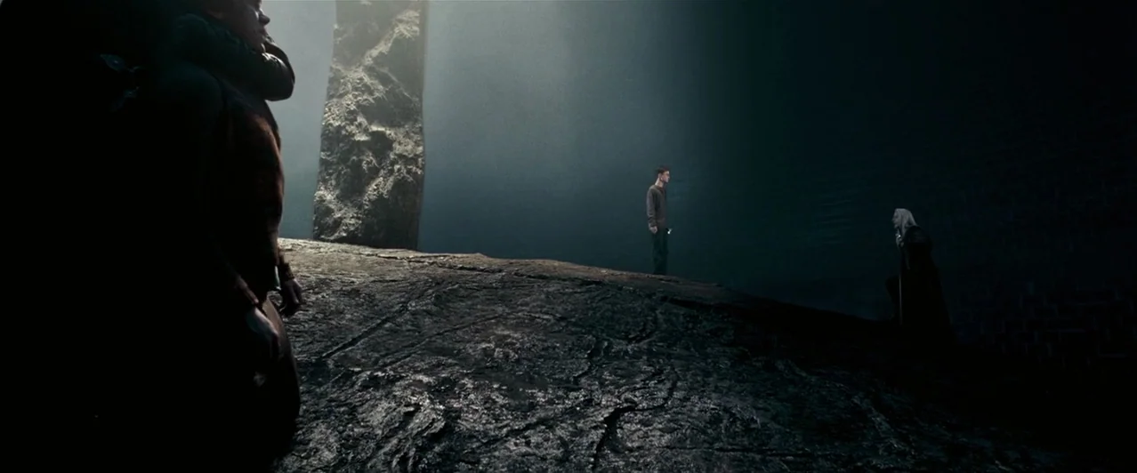 Harry Potter & The Order of the Phoenix (2007) movie still: wide — A dark subterranean space features a large jagged stone monolith and a rocky…