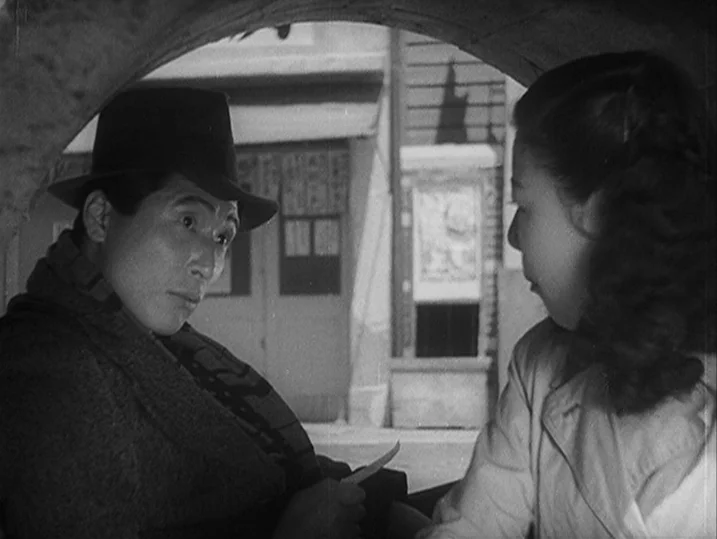 Anatomy of a Relationship (1976) movie still: medium — Two individuals stand in the shadowed opening of an arched architectural structure outdoors.…
