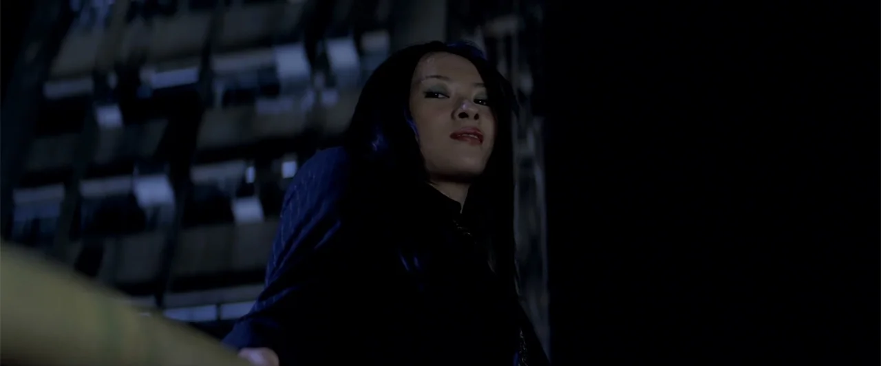 Rush Hour 2 (2001) movie still: medium — A dark balcony at night overlooks a blurred architectural structure in the background. A young woman with…