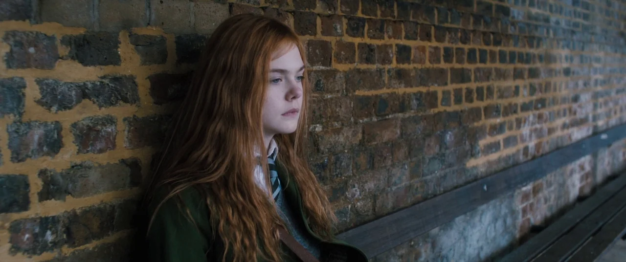 Ginger & Rosa (2012) movie still: medium — A teenage girl with long auburn hair stands against a weathered red brick wall. The girl in a school…